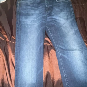 Blå jeans från Hugo Boss - Snygga blå jeans från Hugo Boss med klassisk femficksdesign och diskret tvätt. Jeansen har raka ben och normal passform, perfekt för en stilren look. Materialet är mjukt och följsamt i bomull med en hint av stretch för extra komfort.