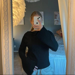 Blus från lager157 - Svart  tröja med snygg struktur och vida, långa ärmar. Tröjan har ett diskret mönster i  som ger en cool look. Perfekt för dig som gillar stilrena och bekväma plagg med det lilla extra.