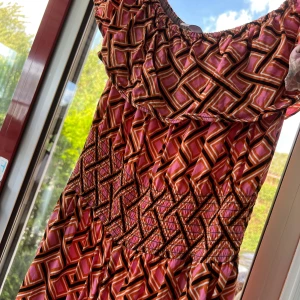 Mönstrad byxdress från Amisu, strl 42 - Färgstark byxdress från Amisu i storlek 42 med grafiskt mönster i rosa, orange och svart. Vida ben och smockad midja för skön passform. Off shoulder-modell med resår upptill. Perfekt för dig som gillar statement-plagg!
