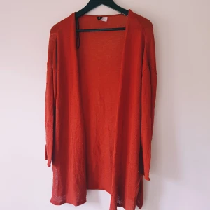 Röd kofta från H&M Divided strl M - Säljer en röd, öppen kofta från H&M Divided i storlek M. Koftan är stickad, har lång ärm och en loose passform. Perfekt att slänga över en t-shirt eller linne för en chill look.  Helt skick dock noppror & tråddragningar