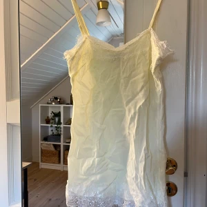 Ljusgul spetslinnetopp  - Supersöt ljusgul linnetopp med tunna axelband och fina spetsdetaljer upptill och nertill. Toppens material är mjukt och flowy, perfekt för varma dagar. Spetsen ger en romantisk vibe och toppen är lätt att styla med jeans eller kjol.