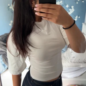 Vit croppad topp med knyt i ryggen - Säljer en vit croppad topp med halvlånga ärmar och snygg knytning i ryggen som ger öppen rygg-effekt. Toppens material är mjukt och stretchigt, ❤️ jag säljer den då jag knappt har haft den på mig och då känns de onödigt att ha kvar den. Skriv om ni vill ha fler bilder. Den är i ny skick har haft den en gång ute annars har den bara legat i min garderob. Den är köpt från Gina ❤️köpt för 300kr