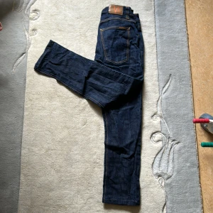 Mörkblå Nudie Jeans - Säljer ett par mörkblå jeans från Nudie Jeans i klassisk rak modell. Jeansen har använts två gånger och är helt nya, pris kan diskuteras