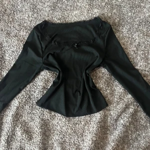 Svart ribbad lång ärmad tröja med spets och en rosett - Använd fåtal gånger men är fortfarande i väldigt bra skick. Säljer pga att det inte är min stil längre.