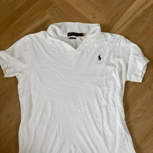 Vit Polo Ralph Lauren polo slim fit - Vit Polo från Polo Ralph Lauren i bomull med klassisk krage och broderad marinblå logga på bröstet. Modellen är custom slim fit och har korta ärmar. Perfekt för en clean och stilren look.