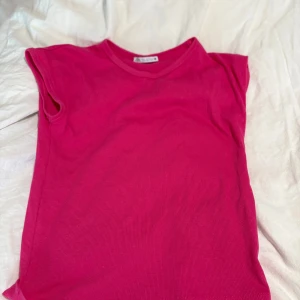 Rosa ärmlös ribbad topp - Snygg rosa topp med ribbad struktur och ärmlös design. Perfekt för dig som gillar en enkel men trendig look. Rund halsringning och mjukt material som sitter skönt mot kroppen.