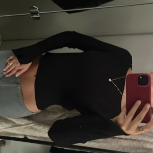 Svart ribbad topp från H&M - Säljer en svart, ribbad långärmad topp från H&M. Modellen är croppad med rund halsringning. 