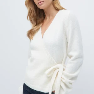 Vit omlottkofta med knytband - Supermjuk vit omlottkofta med v-ringning och knytband i sidan. Koftan har lång ärm och är stickad i ett fluffigt material som känns riktigt cozy. Perfekt att slänga på sig över ett linne eller t-shirt för en chill look.❤️den är i xs använd cirka 2-3 gånger inga defekter