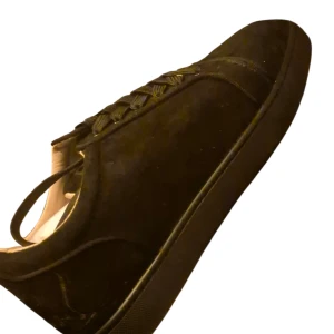 Svarta mockasneakers från Louboutin - Snygga svarta sneakers i mocka från Christian Louboutin med klassisk röd sula och diskreta metalldetaljer på sidan. Skorna har rund tå, snörning och en stilren, minimalistisk design som passar perfekt till streetwear eller en mer dressad look.