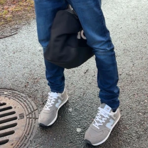 Grå New Balance sneakers med vit detalj - Snygga grå sneakers från New Balance med vita detaljer och klassisk N-logga på sidan. Skorna har vit snörning, platt sula och rund tå. Perfekta för en avslappnad streetstyle-look och passar till jeans eller joggers.