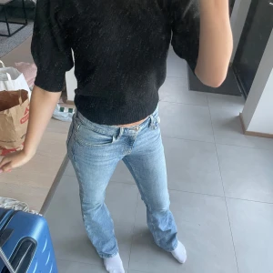 Svart polotröja från JDY XS - Svart polotröja från JDY i stickat material. Tröjan har kortare ärmar med lätt puff och ribbade muddar vid hals, ärmslut och nederkant. Snygg och enkel modell som är lätt att matcha till jeans eller kjol.