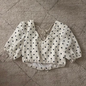 Prickig topp - Supersöt vit topp med svarta prickar i mycket bra skick, knappt använd! Skulle säga att den passar xs, s och m då banden där bak går att justera💞