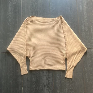 Beige ribbad tröja från Gina Tricot - Säljer en beige ribbad tröja från Gina Tricot i storlek M. Tröjan har breda, långa ärmar och en croppad passform. 