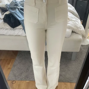 Beiga bootcut jeans  - Snygga beiga jeans från Dr. Denim med bootcut passform och hög midja. Byxorna har stora fickor fram och bak, klassisk knappstängning och är tillverkade i ett mjukt bomullsmaterial. Perfekta för dig som gillar en clean och stilren look.