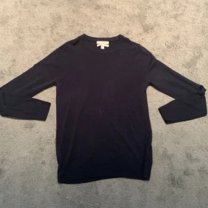 Mörkblå stickad tröja  - En stilren mörkblå stickad tröja från Marc O'Polo. Tröjan har rund halsringning och långa ärmar, perfekt för lager-på-lager. Enkel design som funkar till många olika outfits.