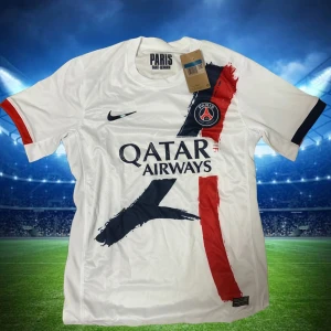  Fotbollströja PSG  - Paris Saint-Germain fotbollströja i vitt med coola penseldrag i rött och mörkblått framtill. PSG-logga på bröstet, Nike Swoosh och Qatar Airways som sponsor. Kortärmad modell i lätt och ventilerande material, perfekt för match eller träning.