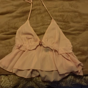 Rosa halterneck topp - Söt rosa halterneck topp med volanger och öppen rygg. Den har aldrig används, så söt för sommaren