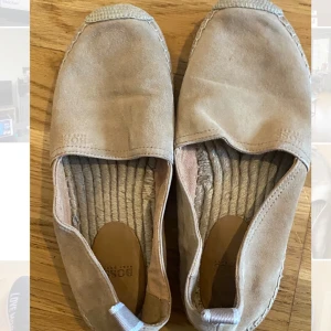 Beige espadrillos från Hugo Boss - Snygga beige espadrillos från Hugo Boss med en klassisk design. Skorna har en ovandel i mocka och en sula med flätad detalj. Perfekta för en avslappnad stil. Använda en gång. 