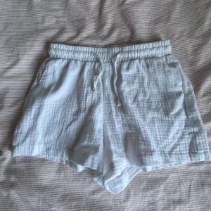 Vita shorts från Gina Tricot - Snygga låga vita shorts från Gina Tricot med elastisk midja och dragsko. Perfekta för varma sommardagar. Tillverkade i ett lätt och luftigt material som ger en bekväm passform.