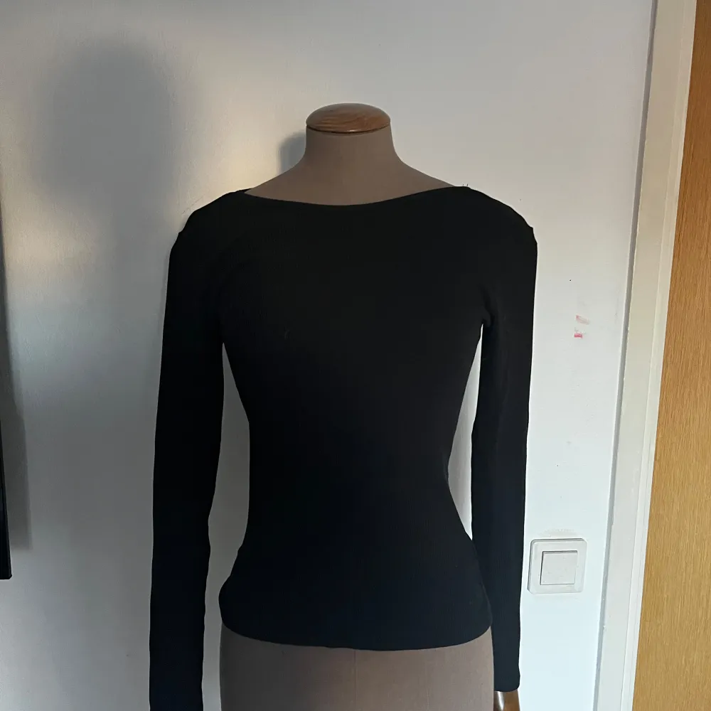 Snygg svart långärmad topp med en elegant och enkel design. Perfekt för att matcha med olika outfits. . Neuletakit & Villapaidat.