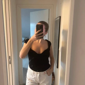 Svart stickad topp - Säljer en stilren svart stickad topp med korta ärmar. Perfekt för en enkel och elegant look. Toppen är figurnära och passar bra till både jeans och kjol.