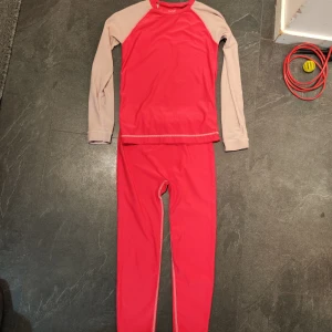 Röd och beige underställ från 157 Funk, lager 157 - Säljer ett röd och rosa underställ från 157 Funk. Tröjan har långa ärmar och är tillverkad i en mjuk polyesterblandning med elastan för extra stretch. Perfekt för kyliga dagar och aktiviteter utomhus. Passar bra under vinterkläder.