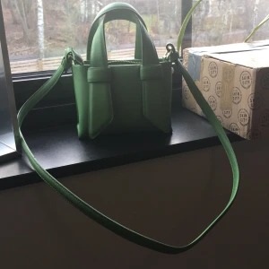 Grön axelväska med dragkedja - Snygg grön axelväska  med praktisk dragkedja. Väskan har både handtag och en justerbar axelrem för flexibel användning. Perfekt för att ge en färgklick till din outfit!