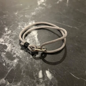 Grått armband med metallspänne - Justerbart grått armband med ett stilrent metallspänne. Armbandet har en enkel och modern design som passar till många olika stilar. Perfekt för både vardag och speciella tillfällen. 