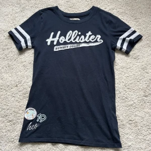 Hollister T-shirt  - Så snygg och somrig T-shirt med fina detaljer! Säljer eftersom jag har tröttnat lite på den. Köpte secondhand 2022 och har använt en del, men mycket bra skick🙌 materialet är stretchigt, passar xs-m