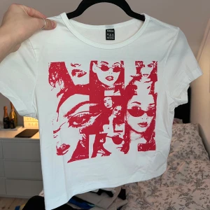 Vit t-shirt med rött tryck - Säljer en vit t-shirt med ett coolt rött tryck av olika ansikten. T-shirten har en normal passform och korta ärmar, perfekt för en avslappnad stil. Materialet är mjukt och bekvämt. Liten i storleken!! Passar till S/M. Aldrig använd. Önskar du veta exakta mått? Tveka inte att höra av dig!