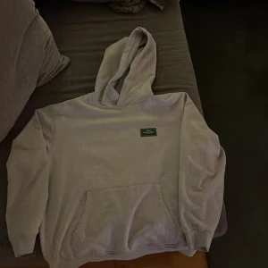 Grå hoodie från Nikben - Säljer en grå hoodie från Nikben pga att den har blivit för liten med texten 'ASPEN' på baksidan och en liten grön etikett med texten 'OFF SEASON' på fram sidan. Hoodien har en klassisk design med känguruficka och ribbade muddar. Perfekt för en avslappnad stil. Även en laganing i midje resåren.