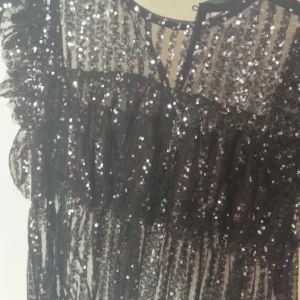 Glittrig tröja med volangdetaljer - Glittrig tröja med paljetter. Köpte den till nyår och har bara andvänt den en gång. Köptes på Gina tricot Young och är i storlek 146/152 och passar mig som har xs 