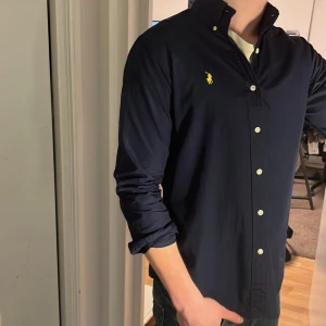 Ralph Lauren Skjorta - Tja säljer en Ralph lauren skjorta i färgen marinblå och i storlek S passar 170-180 cm ungefär. Nypris 1595 KR mitt pris 299 KR. Inga defekter som hål eller fläckar. Skriv vid frågor eller funderingar.