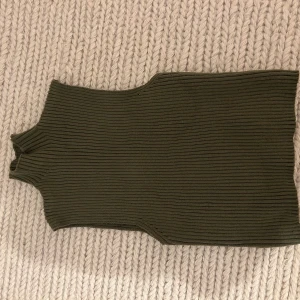 Olivgrön ribbad ärmlös topp från zara - Snygg olivgrön ribbad topp med hög krage. Perfekt för lager-på-lager eller som den är. Den ärmlösa designen gör den idealisk för varmare dagar eller som baslager under en jacka. Är från zara oxh är aldrig använd, hör av er vid frågor