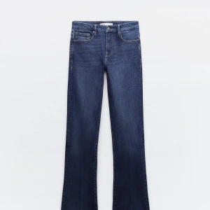 Blå jeans från Zara - Snygga blå jeans från Zara med klassisk femficksdesign och knappgylf. Perfekta för en avslappnad stil. De har en bootcut-stil som ger en retro känsla. Färgen är svår att se i bilderna tagna av mig men skulle säga att färgen är mer lik den på bilden från deras hemsida😊