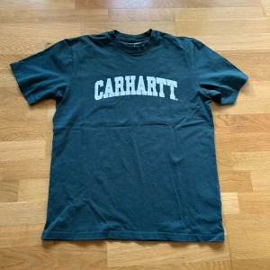Grön Carhartt T-shirt - En fin T-shirt från Carhartt som är sparsamt använd. Den är i mycket fint skick och sitter väldigt bra. Lite mindre i storleken.