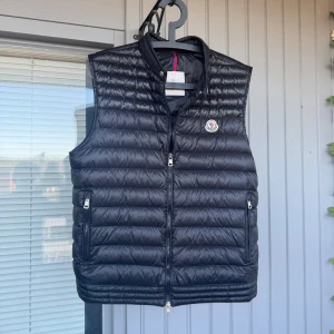 Svart dunväst från Moncler - Säljer en sjukt snygg moncler väst som är perfekt inför våren.           | storlek - 4 som motsvarar M/L västen är självklart äkta ( äktighetsbevis - bild 4 ) skriv vid frågor eller funderingar ! 