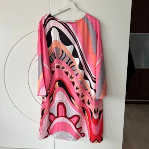 Färgglad mönstrad klänning - Säljer en färgglad klänning med abstrakt mönster i rosa, svart, orange och vit. Klänningen har en lös passform och trekvartsärmar, perfekt för en somrig look. Materialet känns mjukt och luftigt. Märke: Allamode