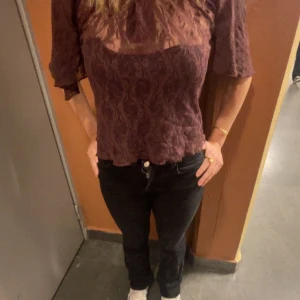 Vinröd blus med mönster - Säljer en elegant vinröd blus med ett subtilt mönster. Blusen har trekvartsärmar och en lätt transparent design som ger en sofistikerad look. Perfekt för att lyfta vilken outfit som helst.