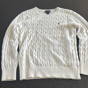 Vit kabelstickad tröja från Ralph Lauren - Säljer en stilren vit kabelstickad tröja från Ralph Lauren. Tröjan har en klassisk design med rund hals och långa ärmar. Perfekt för en elegant och avslappnad look. 🧶✨