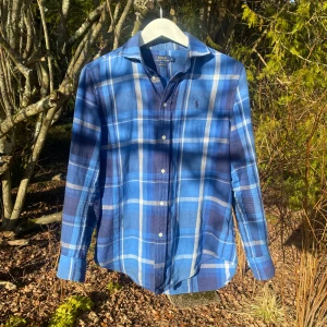Ralph Lauren Flanellskjorta - Säljer en extremt snygg blå rutig skjorta från Ralph Lauren. Skjortan har långa ärmar och knappar framtill. Den är i en relaxed fit och har ett diskret broderat logotypmärke på bröstet. Perfekta plagget till din garderob. Storlek 4 är S. Plagget är i extremt bra skick.