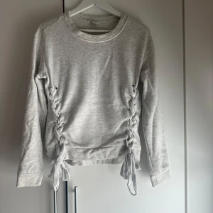 Grå tröja med snörning - Säljer en stilren grå tröja med långa ärmar och snygg snörning på sidorna. Strolek: xs🩷🫶🏼