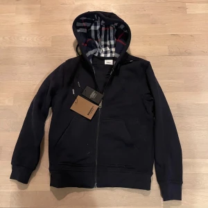 Burberry hoodie - Navy/ Mörkblå Burberry hoodie zip up till ett väldigt billigt pris användt 2 gånger Storlek S lapparna kommer inte med eftersom jag slarvat bort dem den är självklart äkta.  Kostar ny runt 5000                       PRIS ÄR INTE HUGGET I STEN