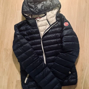 COLMAR Vårjacka - Snygg mörkblå vårjacka från Colmar med huva och dragkedja. Jackan har en quiltad design och vita detaljer vid dragkedjorna. På huvan finns en tråd som lossnat, dock går det inte att se när den är på💘 öppen för prisförslag!!