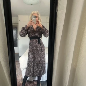 Blommig långklänning - Säljer en vacker blommig långklänning. Klänningen har långa ärmar och ett fint fall. Perfekt för en stilfull look. (Eget bälte)