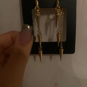 Guldörhängen med kedjor och spetsar - Snygga guldörhängen med långa kedjor och spetsiga detaljer. Perfekta för att ge en edgy touch till din outfit. De hängande kedjorna ger en cool och modern look.