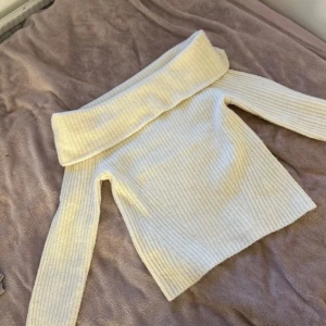 Vit ribbad offshoulder tröja från H&M - Säljer en stilren vit ribbad offshoulder tröja från H&M. Perfekt för en trendig look med sin breda krage och långa ärmar. Tröjan är mjuk och bekväm, idealisk för kyligare dagar. Passar bra till både jeans och kjol. 🌟
