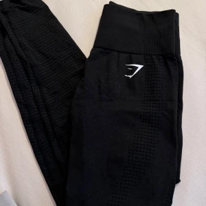 Svarta leggings från Gymshark - Snygga svarta leggings från Gymshark med hög midja och diskret mönster. Perfekta för träning med en tight passform som ger bra stöd. Tillverkade i ett stretchigt material för maximal komfort.
