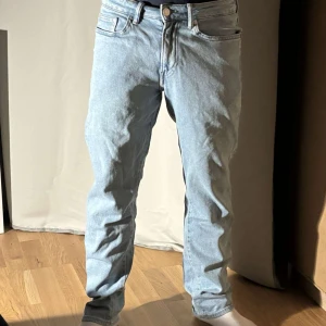 Ljusblå jeansbyxor  - Snygga ljusblå jeans med klassisk femficksdesign och knappgylf. Perfekta för en avslappnad stil. De har en rak passform och är tillverkade i ett bekvämt denimtyg.