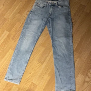 Ljusblå jeans från H&M - Säljer ett par ljusblå jeans från H&M i regular fit. De har en klassisk femficksdesign och är tillverkade i ett bekvämt denimtyg. Perfekta för en avslappnad stil. Hör av er för ytterligare frågor